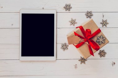 Üstten Görünüm tablet ve hediye kutusu beyaz ahşap geri üzerine kar taneleri ile