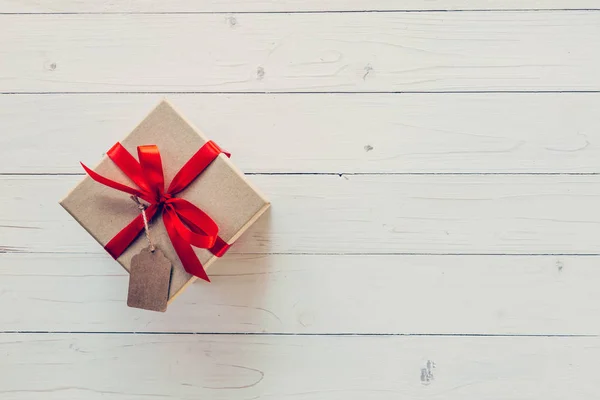 Caja de regalo marrón con etiqueta sobre fondo de madera. Caja de regalo vintage o — Foto de Stock