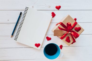 Defter, kahve fincanı, hediye kutusu, kırmızı kurdele, etiket ve kalem yukarıda