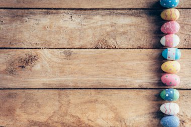 Alanı olan ahşap arka plan üzerinde renkli pastel Paskalya yumurtaları. Tonda vintage.
