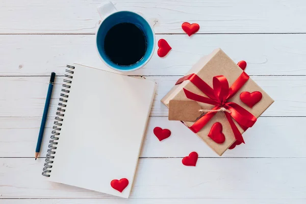 Sopra notebook, tazza di caffè, confezione regalo, nastro rosso, etichetta e matita — Foto Stock