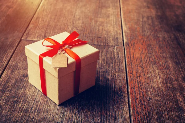 Caja de regalo marrón y cinta roja con etiqueta sobre fondo de madera con s — Foto de Stock