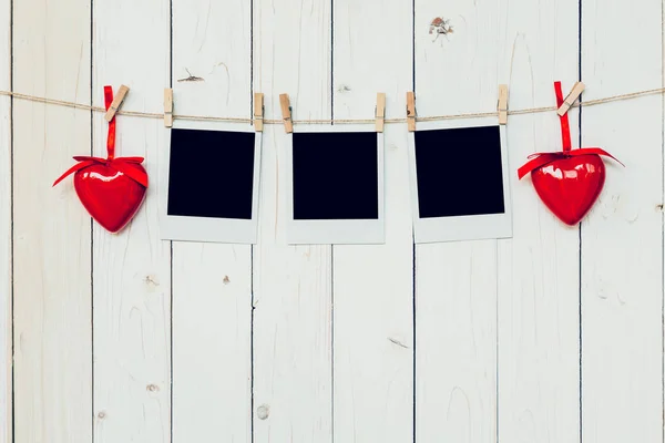 Three photo frame blank and red heart hanging on white wood back — Stock Photo, Image
