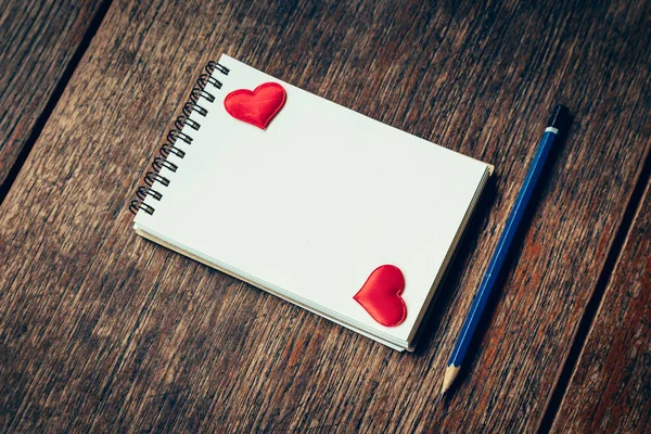 Blank notebook and red heart with pencil on wood background with — Stock Photo, Image