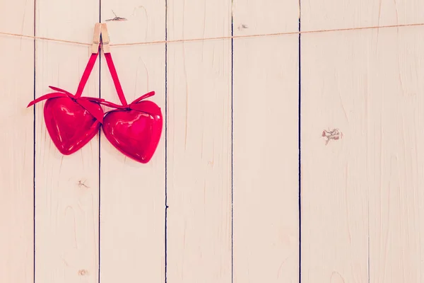 Dos corazones rojos colgando sobre fondo de madera blanca con espacio . — Foto de Stock