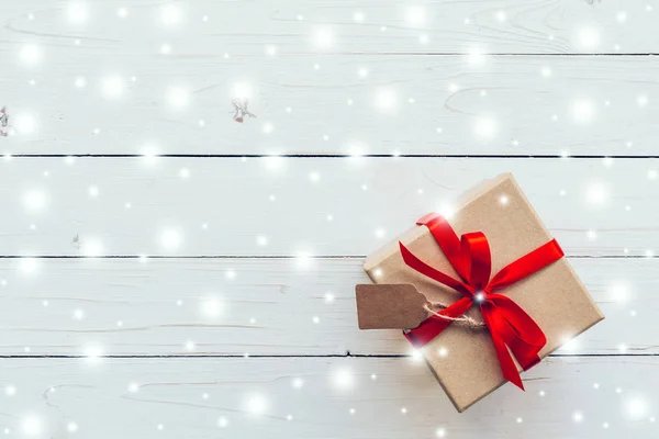 Arriba marrón Caja de regalo y cinta roja, Nieve con etiqueta en madera blanca — Foto de Stock
