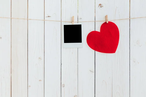 Red heart and photo frame blank hanging at clothesline on wood w — Stock Photo, Image