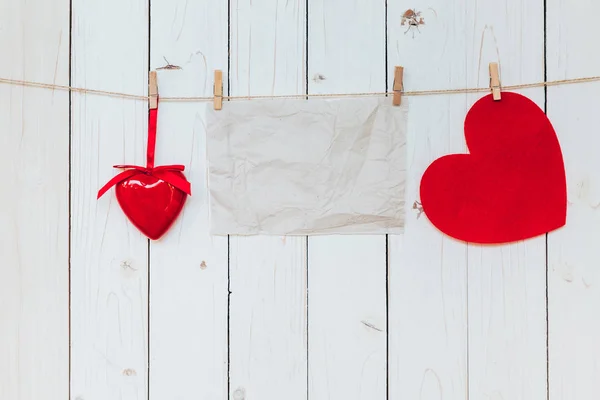 Red heart and old paper blank hanging at clothesline on wood whi — Stock Photo, Image