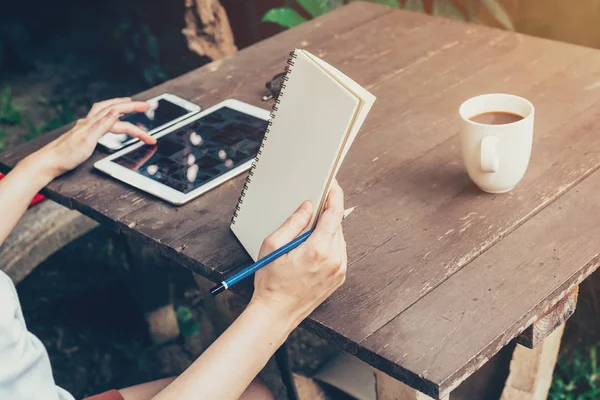 Hand kvinna med surfplatta och innehav notebook på bord trä på co — Stockfoto