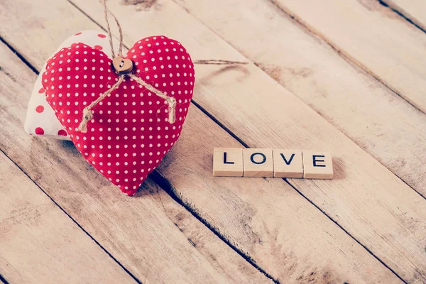 Tejido de corazón y texto de madera de LOVE sobre fondo de mesa de madera . — Foto de Stock