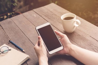 holding ve v ile ahşap masa üzerinde telefon kullanarak el kadın kapatmak