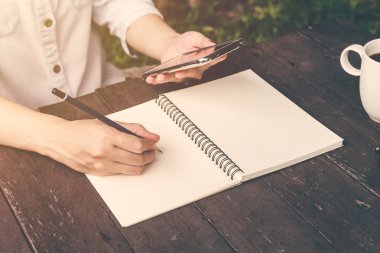 defter ve holding telefon üzerinde ahşap t yazma el kadın kapatmak