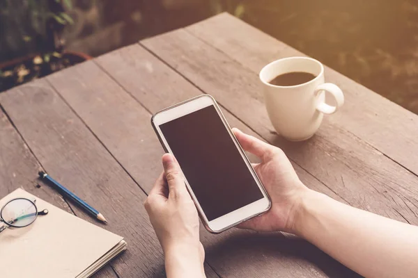 Stäng upp handen kvinna holding och använder telefonen på trä bord med v — Stockfoto