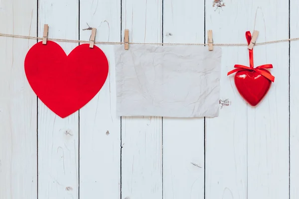 Red heart and old paper blank hanging at clothesline on wood whi — Stock Photo, Image