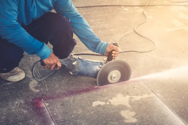 Крупним планом рука чоловіка, який ріже бетонну підлогу з машиною . — стокове фото