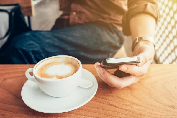Hand man använder telefonen i kafé med vintage filter. — Stockfoto