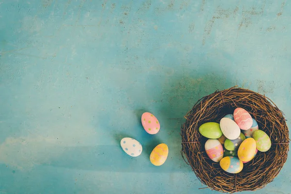 Bunte Ostereier im Nest auf blauem Holz Hintergrund mit Kopie s — Stockfoto