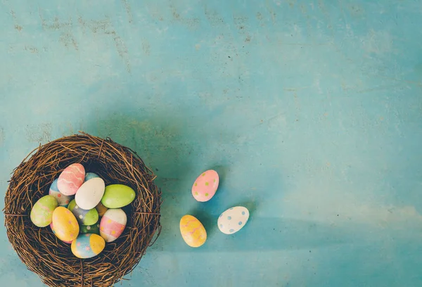 Kleurrijke Pasen eieren in nest op blauwe houten achtergrond met kopie s — Stockfoto