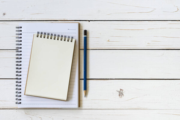 Open notebook with blank pages and pencil on wood table