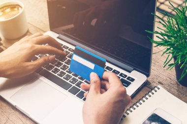 Kredi kartı tutan ve dizüstü bilgisayar kullanarak adam el. Online ödeme.