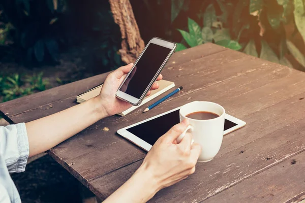 Vrouw hand met telefoon en leeg scherm op houten tafel — Stockfoto