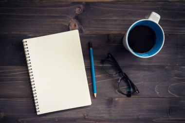 Ofis ahşap masa boş not defteri, kalem, gözlük ve fincan