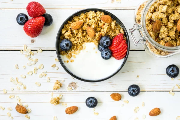 Bowl of granola with yogurt, fresh berries, strawberry on wood t — Stock Photo, Image