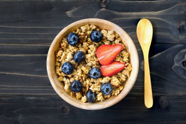 Ev yapımı granola ve uzay ile ahşap masa üzerinde taze çilek.