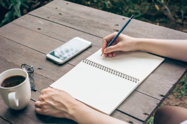Hipster kadın el kahve dükkanında defter kağıt yazma.
