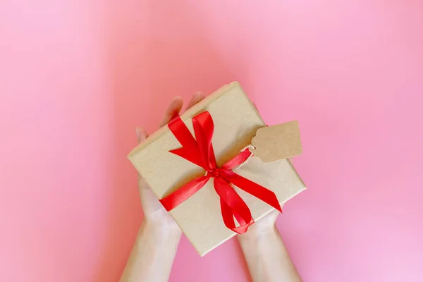 Top view hand woman holding brown gift box for new year on pink — Stock Photo, Image