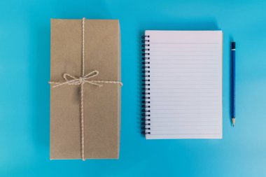 Üstten Görünüm kahverengi hediye kutusu ve defter kağıt üzerinde mavi pastel renk 