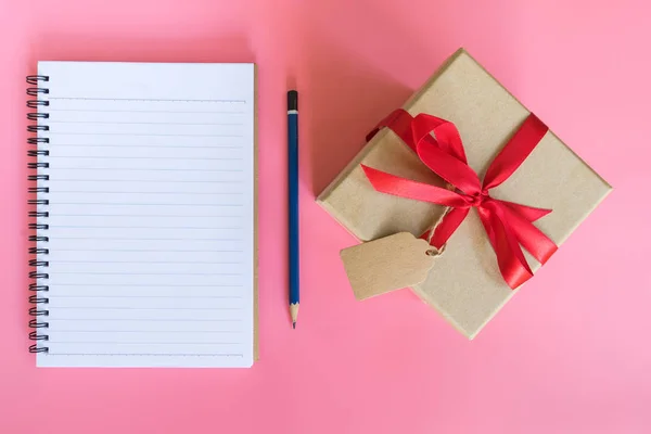 Вид сверху коричневая коробка подарка и ноутбук бумаги на розовый пастельный цвет — стоковое фото