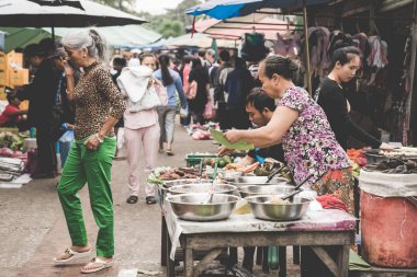  Yemek yemek ve Luang Prabang, Laos üzerinde 13 Kasım, 2017 yılında günlük sabah pazarda satan bir Laotian tepe kabile kadın.