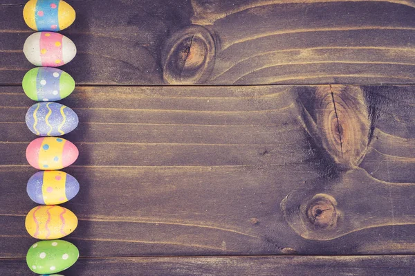 Œufs de Pâques colorés sur fond en bois de planche avec de l'espace . — Photo