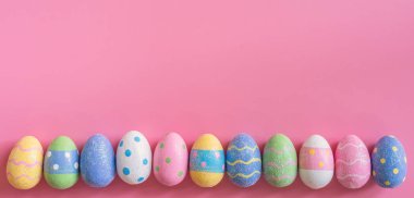 Alanı olan pembe pastel renkli arka plan üzerinde renkli Paskalya yortusu yumurta.