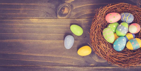 Uovo di Pasqua colorato e nido su sfondo di legno con spazio . — Foto Stock