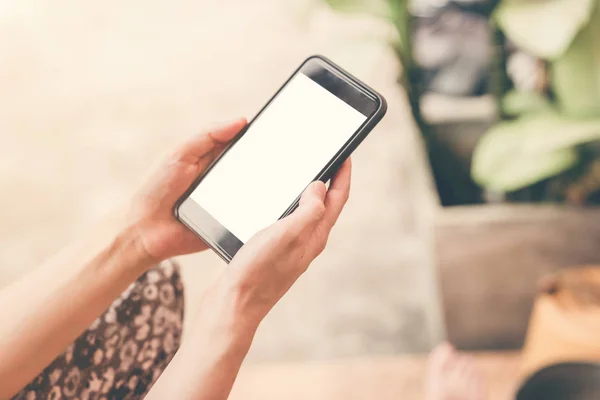 Nahaufnahme einer Frau, die ihr Handy im Garten hält und benutzt. — Stockfoto