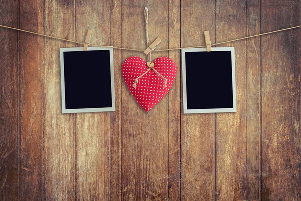 Blank instant photos and red heart hanging on wooden background. — Stock Photo, Image