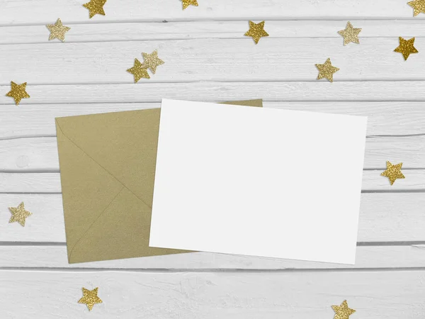 Natale, festa di Capodanno scena mockup con forma a stella dorata confetti scintillanti, carta bianca e busta. Sfondo in legno bianco . — Foto Stock