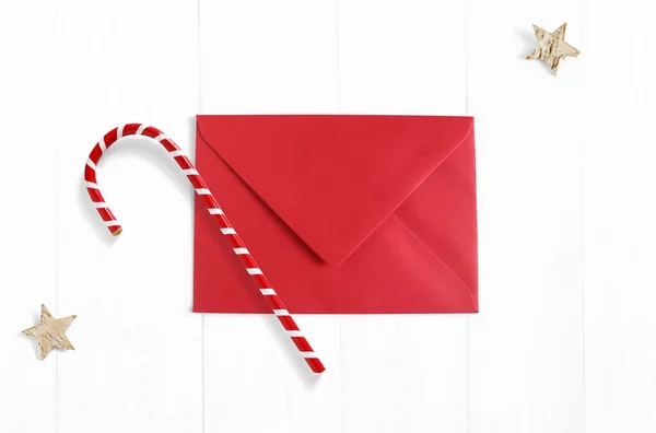 Cena de maquete de Natal com envelope vermelho, decoração de cana-de-açúcar e estrelas feitas de casca de bétula em fundo de madeira branca. Espaço vazio para o seu texto, vista superior . — Fotografia de Stock