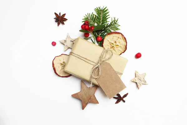 크리스마스 축제 스타일된 재고 이미지 구성입니다. 수 제 선물 상자와 공예 종이 태그, 열매, 나무 별, 말린된 사과 흰색 나무 바탕에 전나무 나무 가지. 평면 위치, 최고 보기. — 스톡 사진