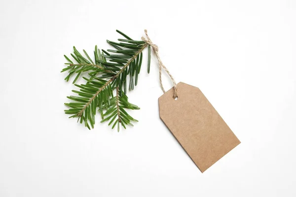 Zbliżenie: craft papieru prezent tag z liny i zielona gałąź jodła na białym tle. Boże Narodzenie składu, widok z góry. — Zdjęcie stockowe