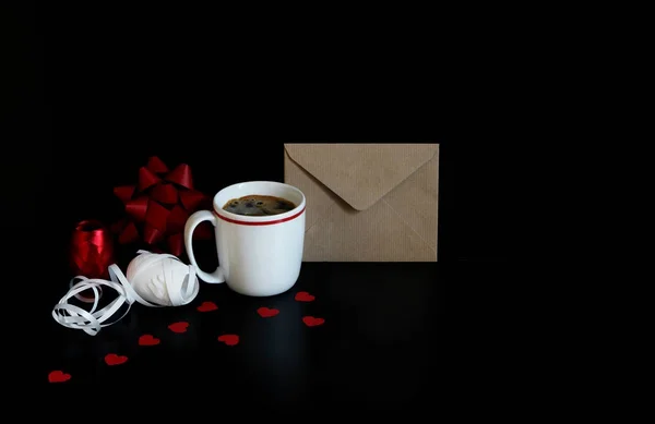 Saint-Valentin ou scène de mariage nature morte avec tasse de café, enveloppe, confettis coeur de papier et rubans cadeaux décoratifs sur fond noir. Concept d'amour. Vue de face. Espace vide pour votre texte . — Photo