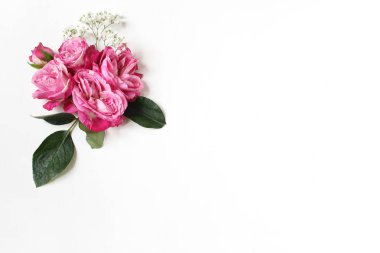 Pembe Gül, yeşil yaprakları ile dekoratif çiçek kompozisyon ve ve babys nefes Gypsophila çiçek beyaz masa arka plan üzerinde. Düz yatıyordu, en iyi görünüm. Düğün ya da doğum günü hazır fotoğraf haberi.