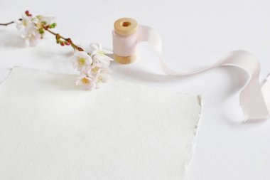 Bir el yapımı kağıt tebrik kartı, biriktirme ipek kurdele ve beyaz masa arka plan üzerinde pembe kiraz çiçekleri ile parlak kadınsı bahar Kırtasiye mockup sahne. Stok fotoğraf düğün haberi.