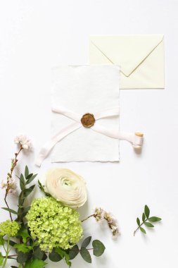 Kadınsı düğün, doğum günü masaüstü maketler. Mühür, şerit ve zarf ile boş tebrik kartı. Okaliptüs şubeleri, pembe kiraz ağacı çiçekleri ve Farsça düğün çiçeği çiçek. Beyaz tablo arka planı