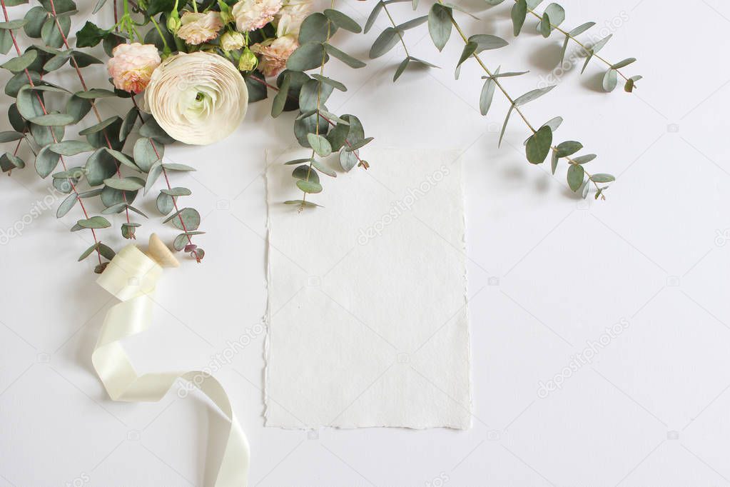 Wedding, birthday mock-up scene with floral bouquet of Persian buttercup, Ranunculus flower, pink roses, eucalyptus leaves and ribbon with blank paper greeting card. Feminine styled image, flat lay.