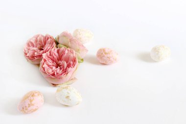 Bahar tebrik kartı, davet. Pembe ve altın noktalar ve gül çiçek beyaz masanın üzerinde yatan Paskalya yumurta beyaz. Kadınsı stok fotoğraf, çiçek kompozisyon tarz.