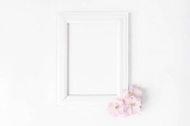Beyaz boş ahşap resim çerçeve mockup pembe Japon kiraz çiçekleri beyaz masanın üzerinde yatan ile. Afiş ürün tasarımı. Stok kadınsı fotoğraf tarz. Ev dekorasyonu. Bahar kavramı.