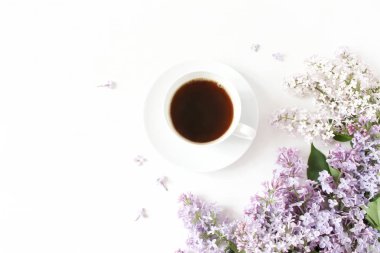 Çiçek kompozisyon fincan kahve ile güzel mor Lila, leylak çiçekler Beyaz ahşap zemin üzerinde yapılmış. Kadınsı Ofis Masası, tarz stok görüntü, boş alanı düz yatıyordu, en iyi Manzaralı.